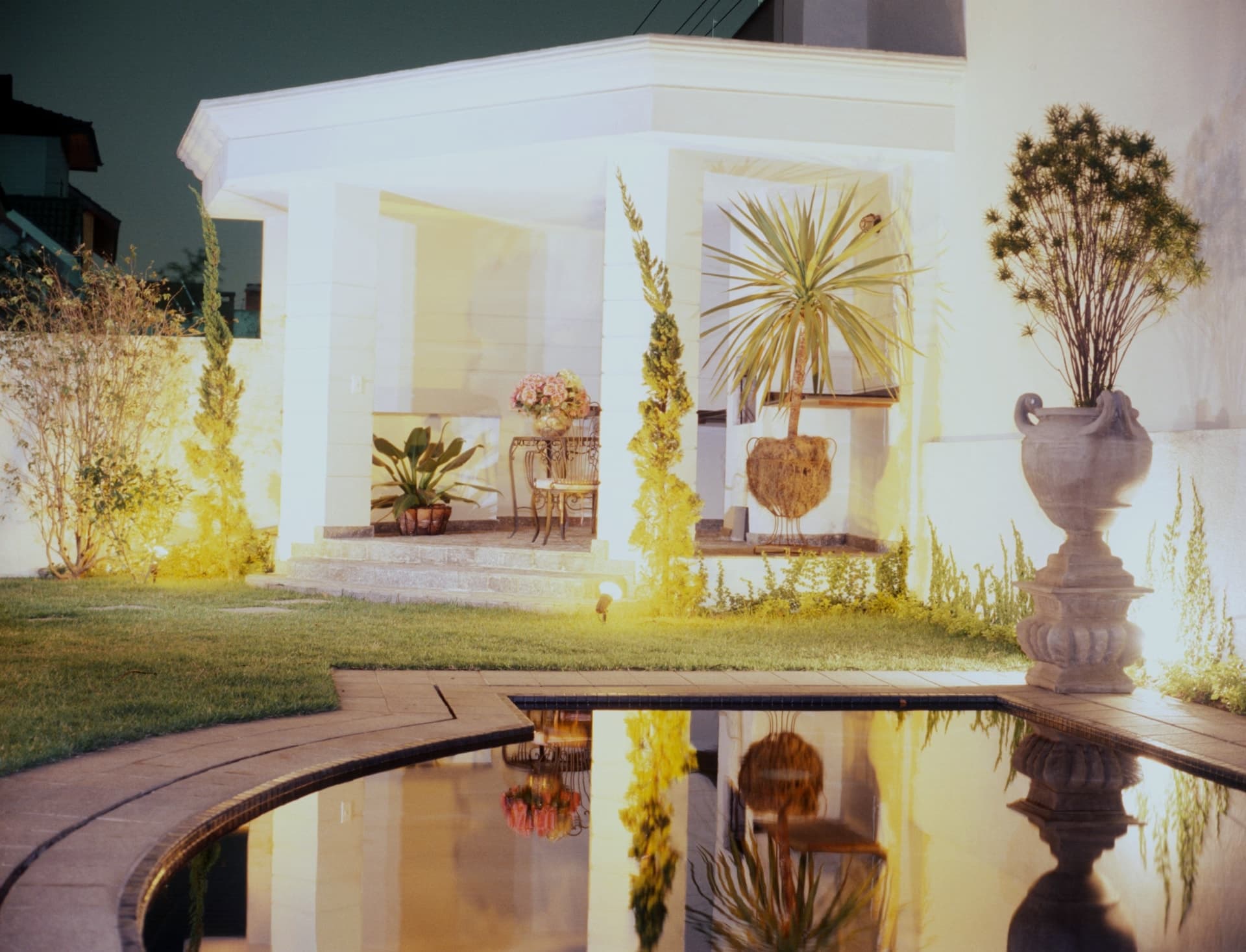 Iluminação noturna refletida no espelho d’água do jardim